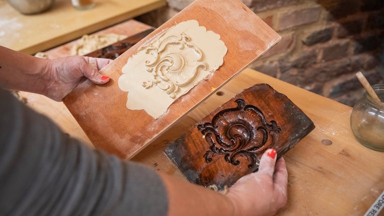 A pair of hands hold a moulding of a section of the new frame
